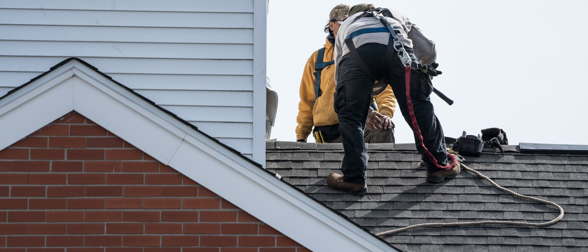Deux hommes travaillent sur le toit d'une maison.