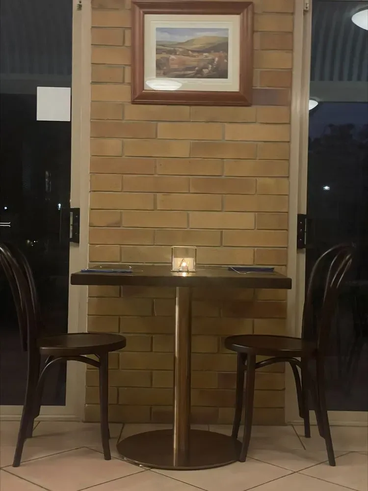 A Small Table With Two Chairs in Front of a Brick Wall — Country Comfort Gin Gin Wild Scotsman Motor Inn in Gin Gin, QLD