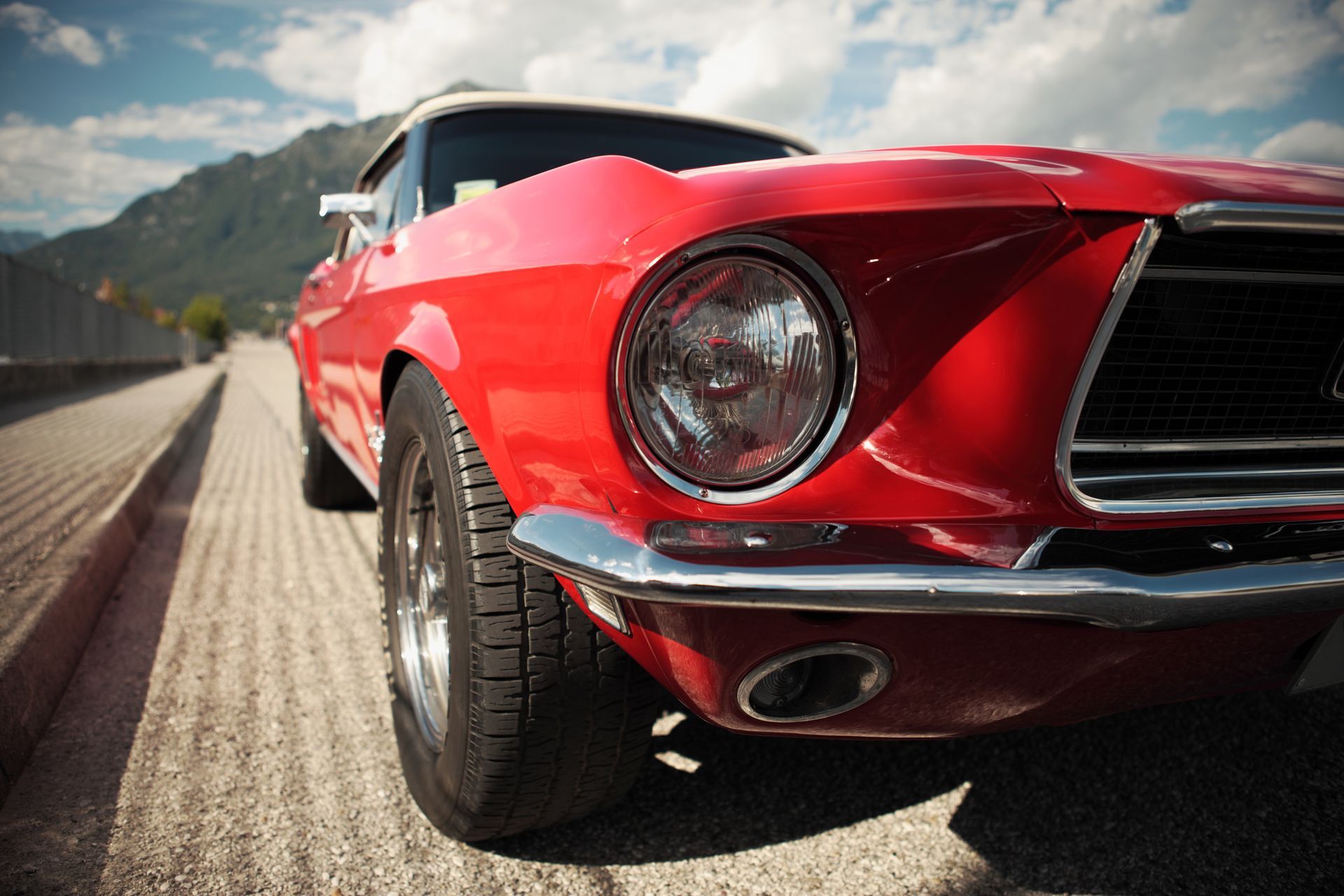 A red mustang is parked on the side of the road.