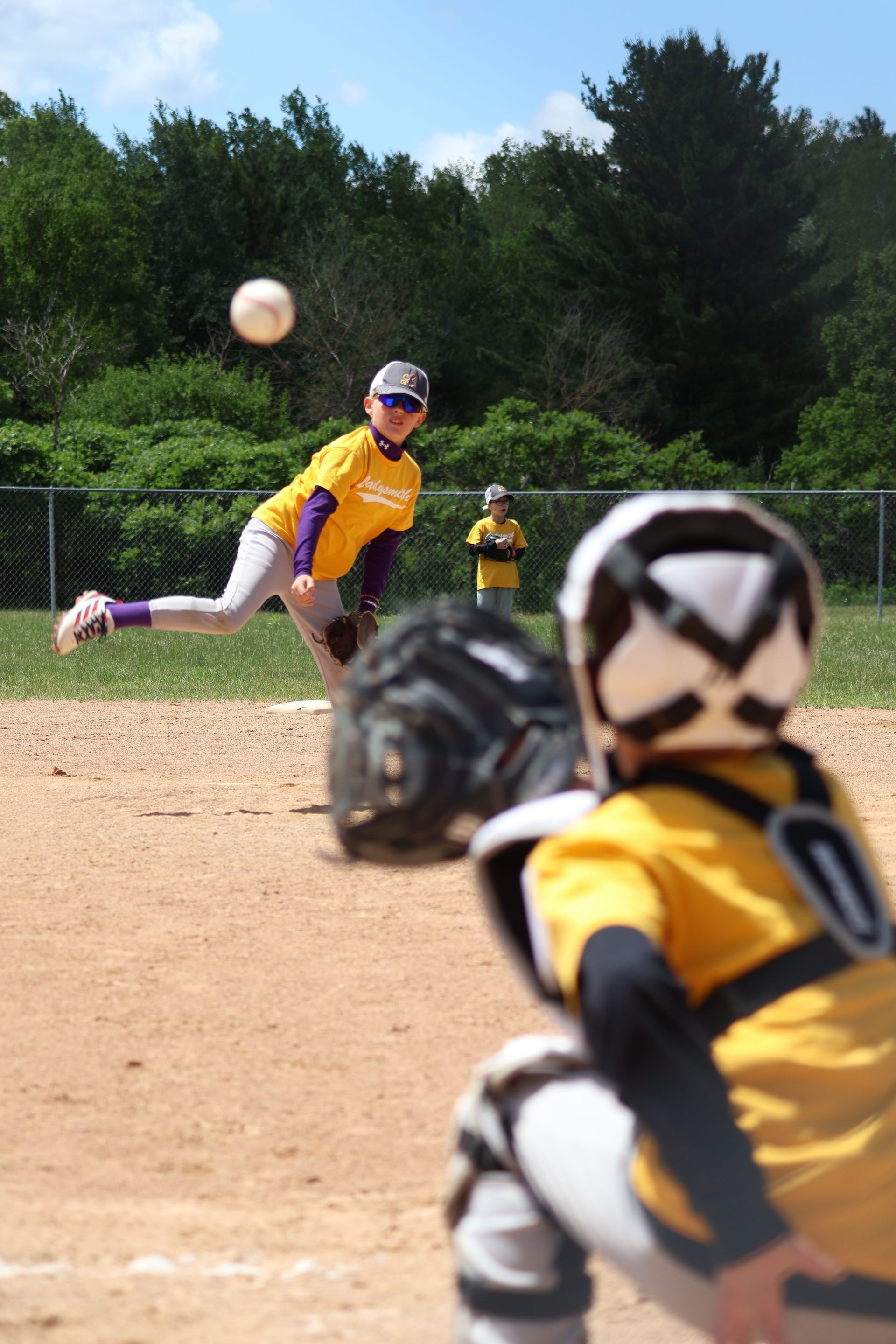Baseball player sliding into base as another player attempts to catch the ball.