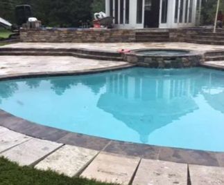 Pool with gazebo reflection. Stone patio with hot tub. Green grass.