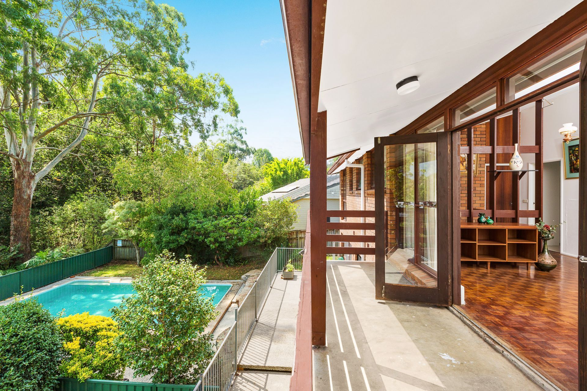 A balcony with a view of a swimming pool and trees.
