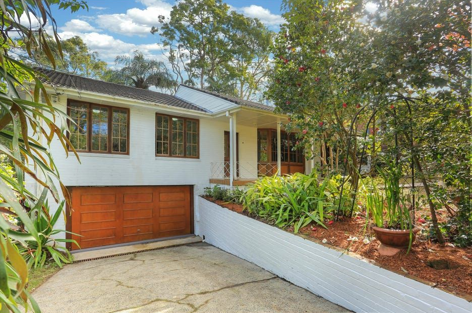 House exterior with white siding, orange garage door, and landscaped front yard on a sunny day
