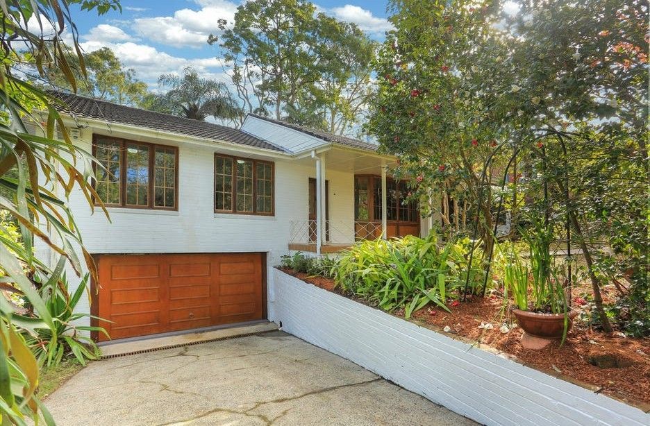 White house with solar panels, wooden garage door, and landscaped front yard by a driveway