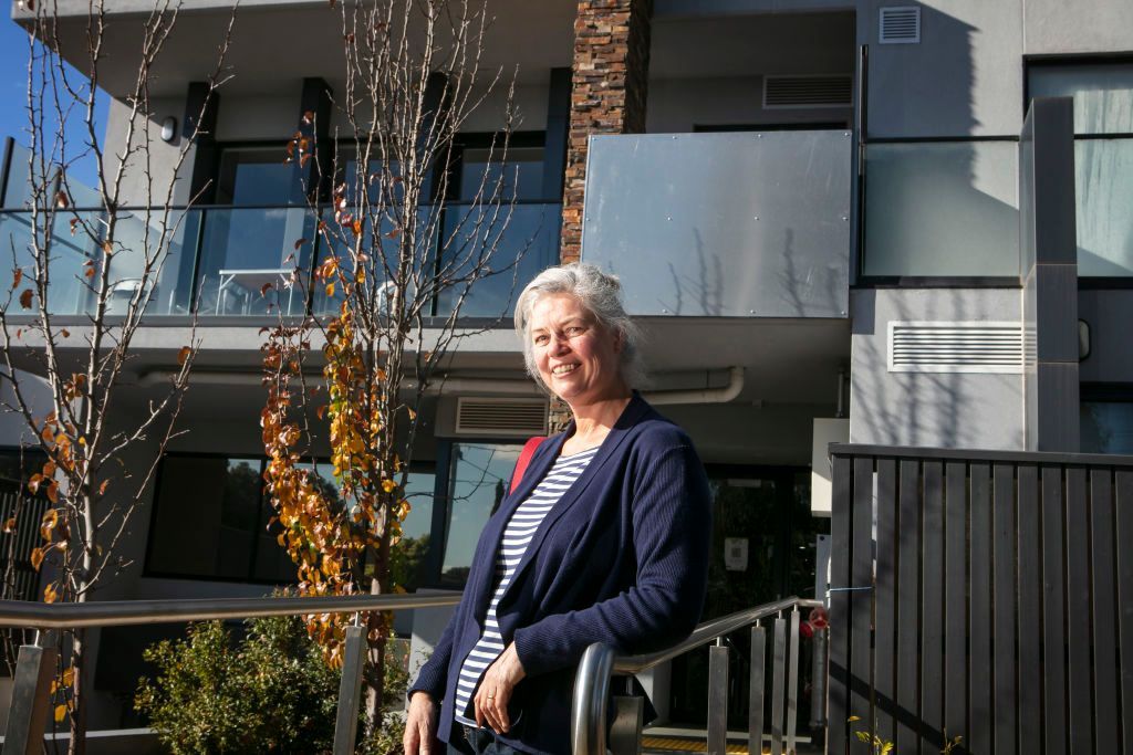 A woman is standing on a railing in front of a building.