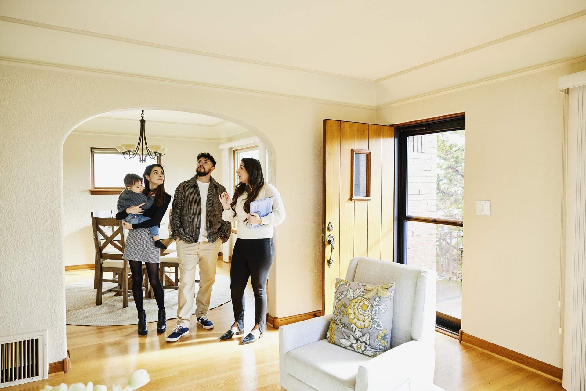 Family touring modern home with hardwood floors and open archway Family touring modern home with hardwood floors and open archway