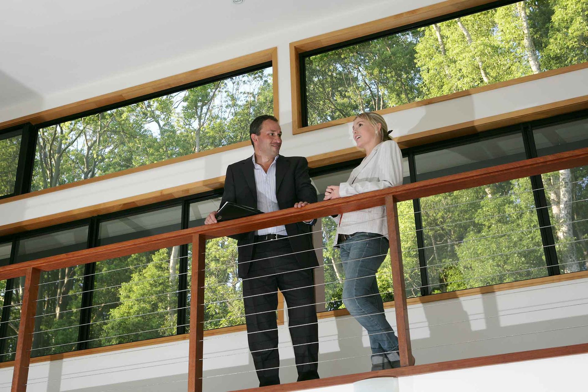 A man and a woman are standing on a balcony talking