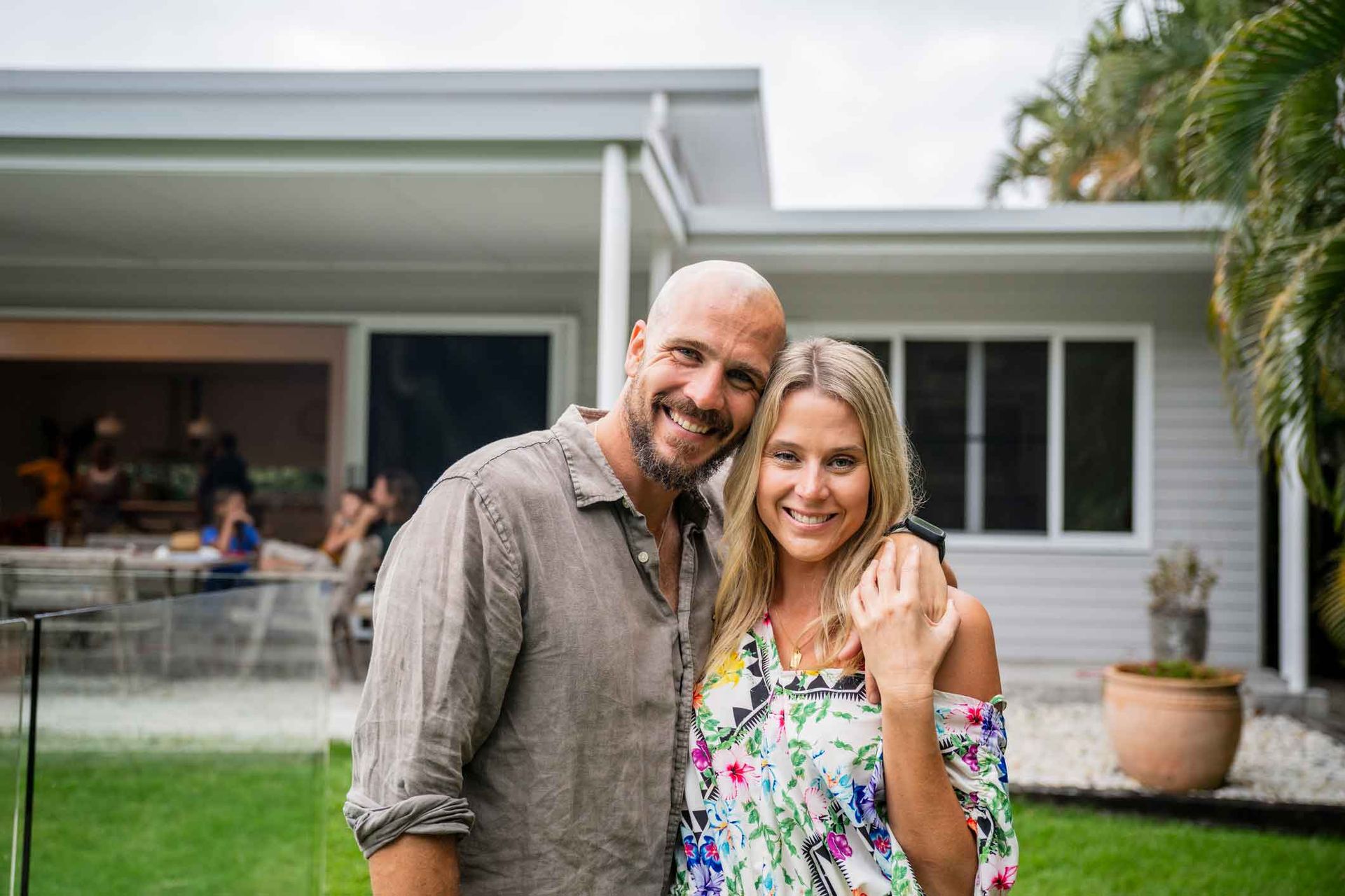 A man and a woman are posing for a picture in front of a house.