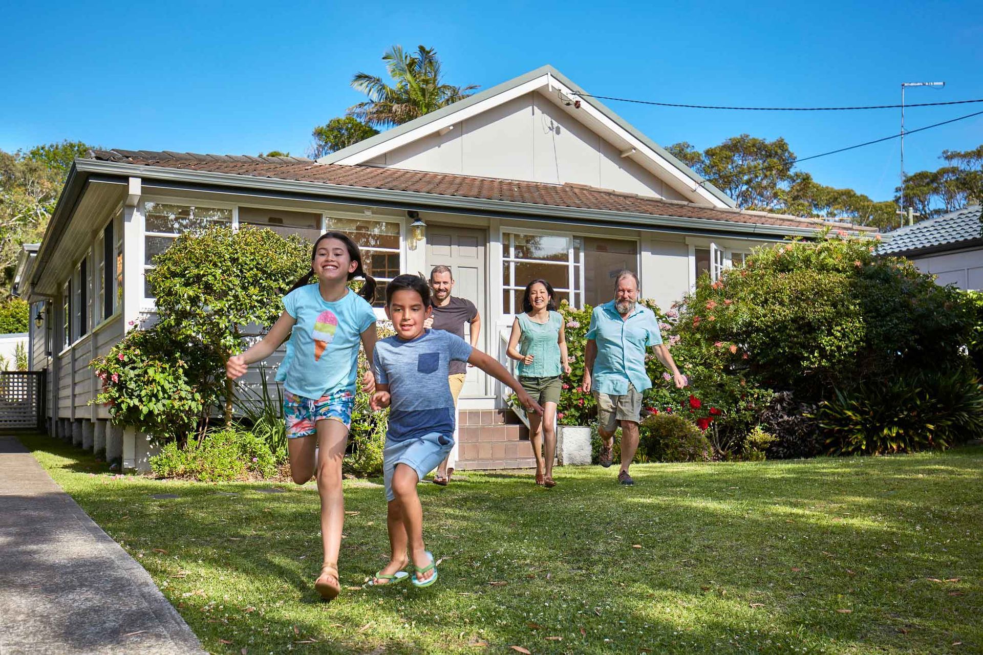 A family is running in front of a house.