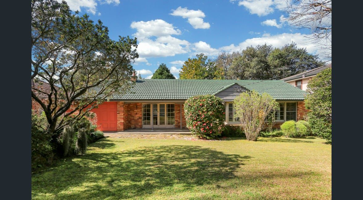 Single-story house with green roof, red and gray exterior, and a grassy front yard under a blue sky.