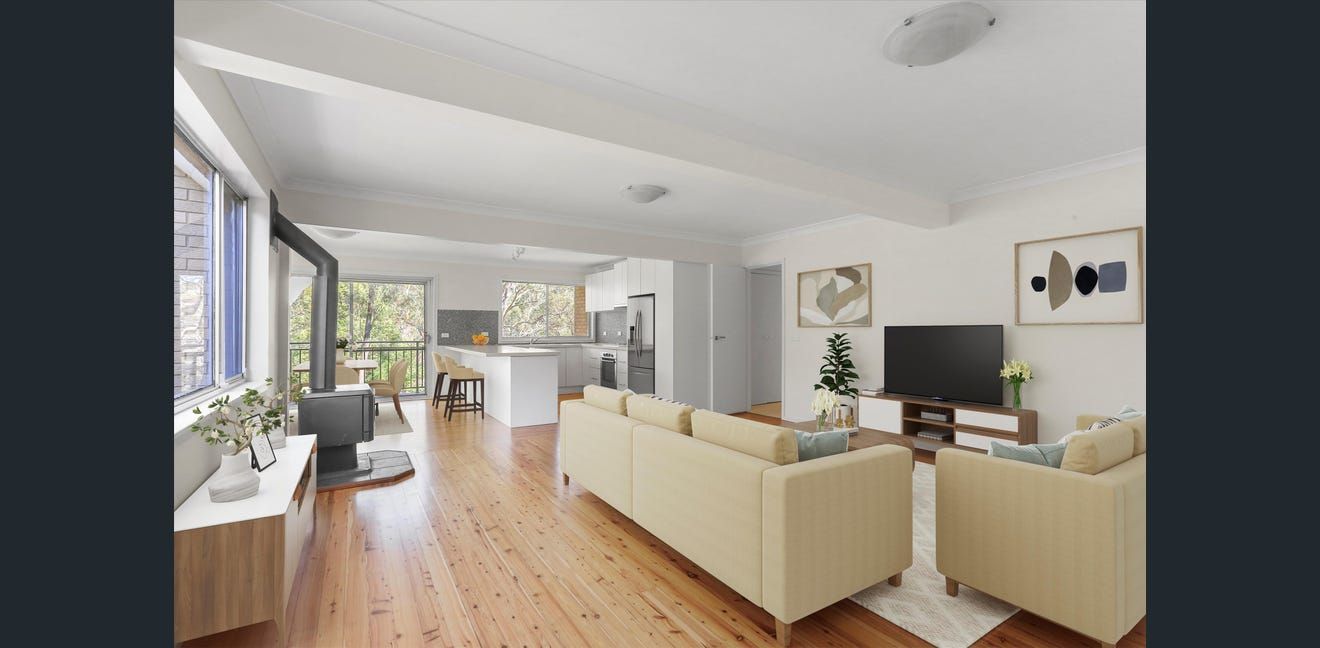 Bright modern living room with cream sofas, wood floors, TV, and large windows overlooking greenery