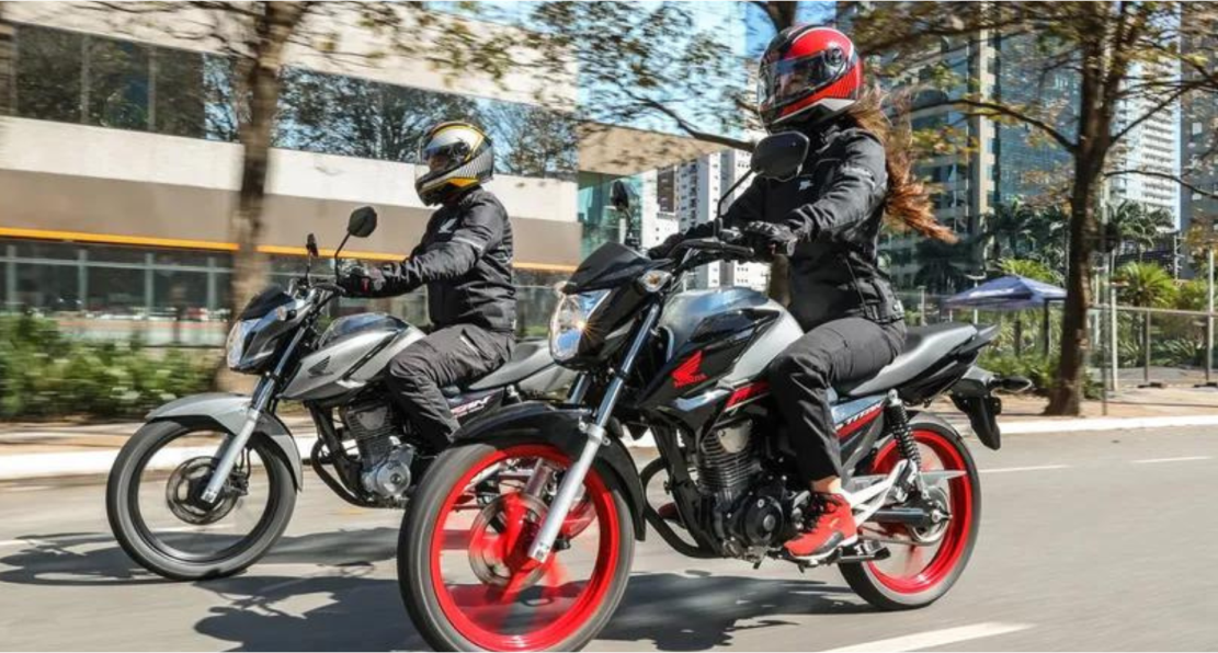 Um homem e uma mulher andam de moto por uma rua.