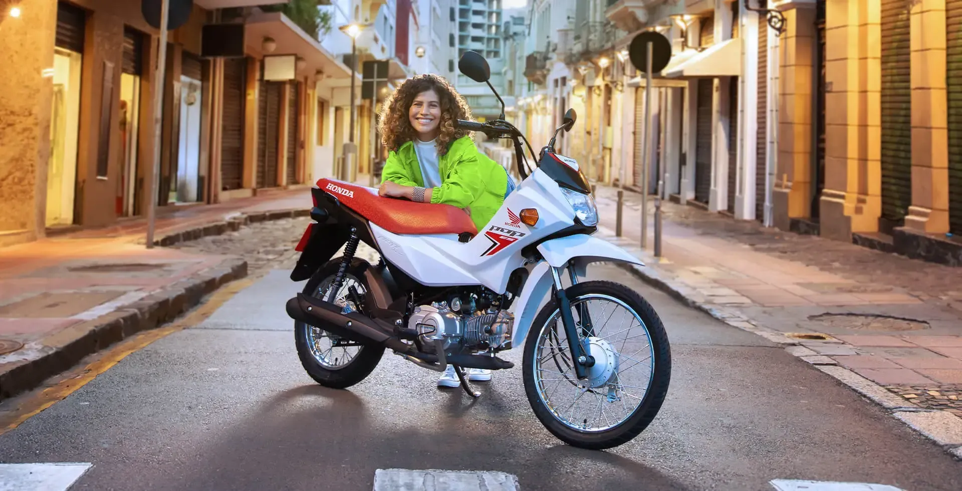 Person in a neon jacket standing beside a white motorcycle on a city street at night