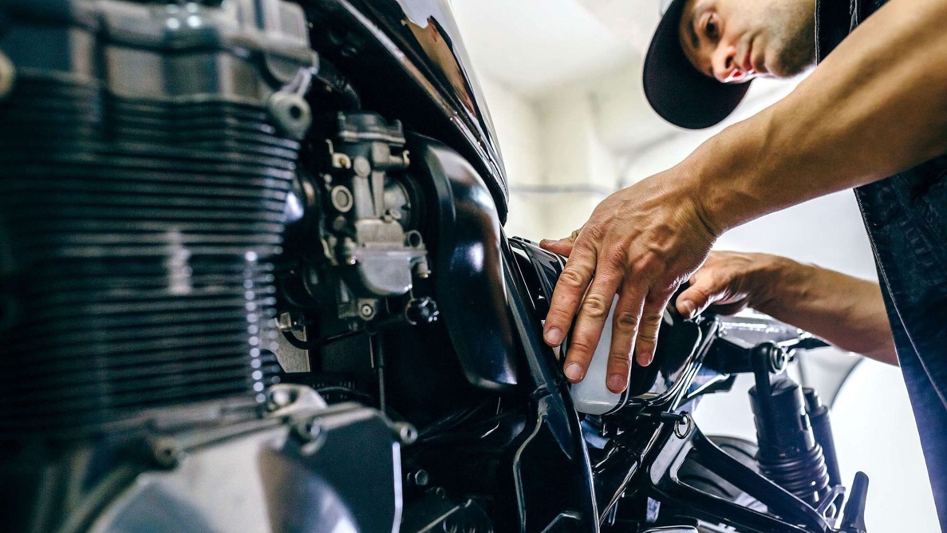 Mechanic working under a car hood with tools in an auto repair shop