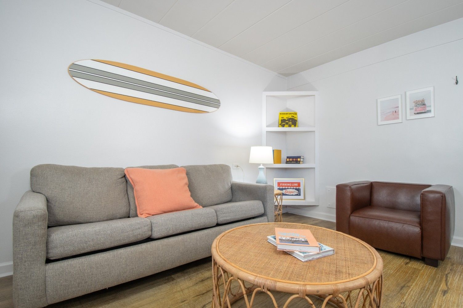 Cozy living room with gray sofa, brown chair, round wicker coffee table, and wall art on white walls