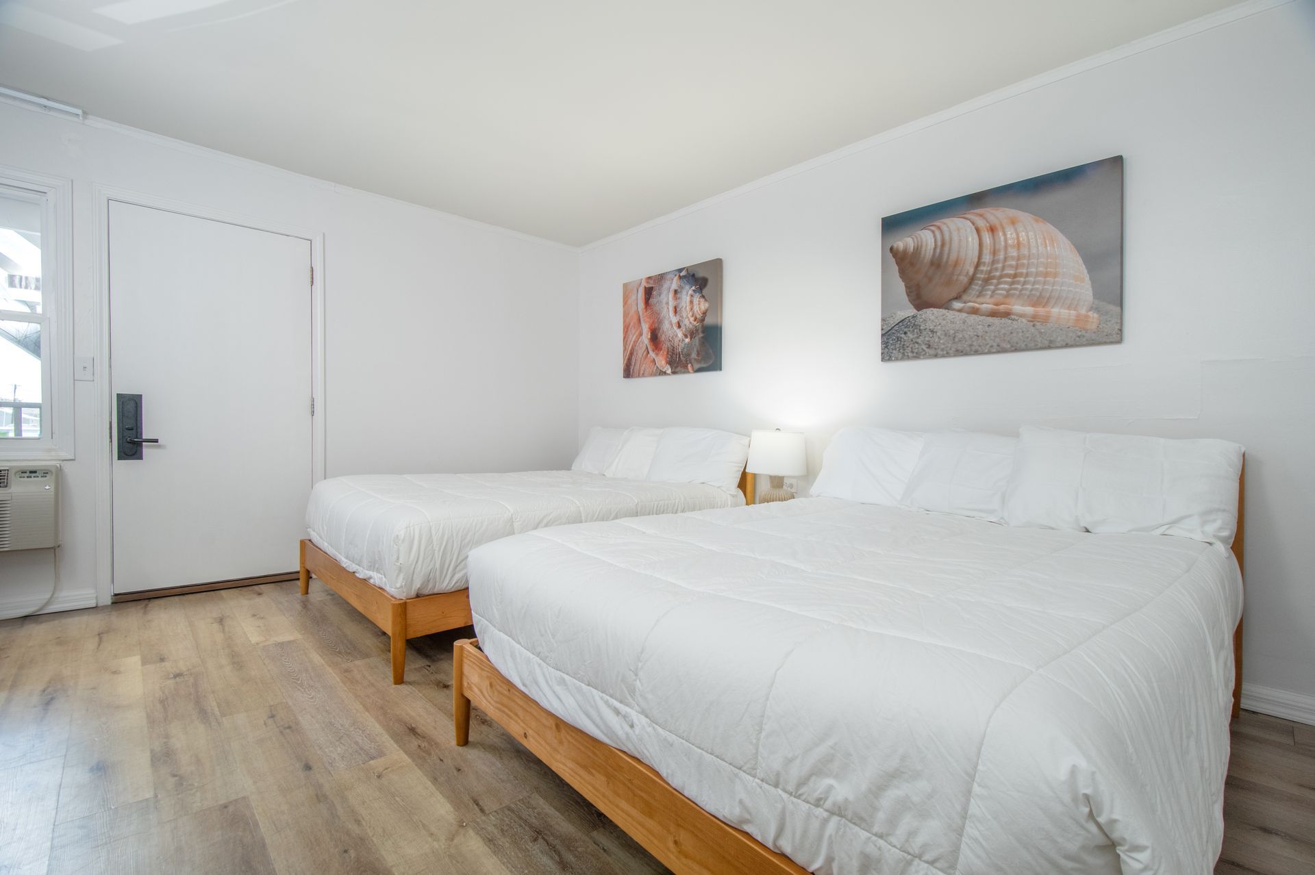 Bright bedroom with two white beds, wood floors, and animal wall art