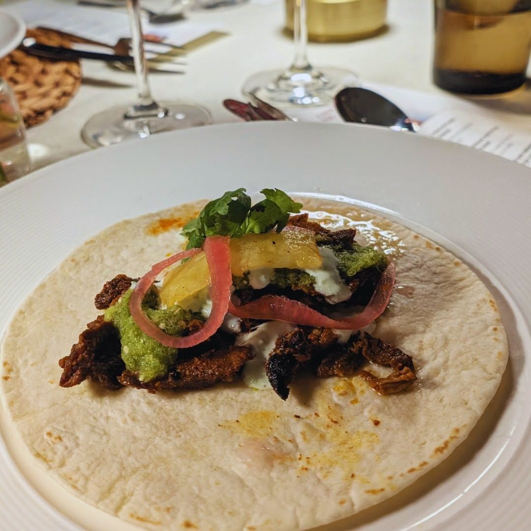 Tortilla wrap with vegetables and herbs on a white plate at a restaurant table