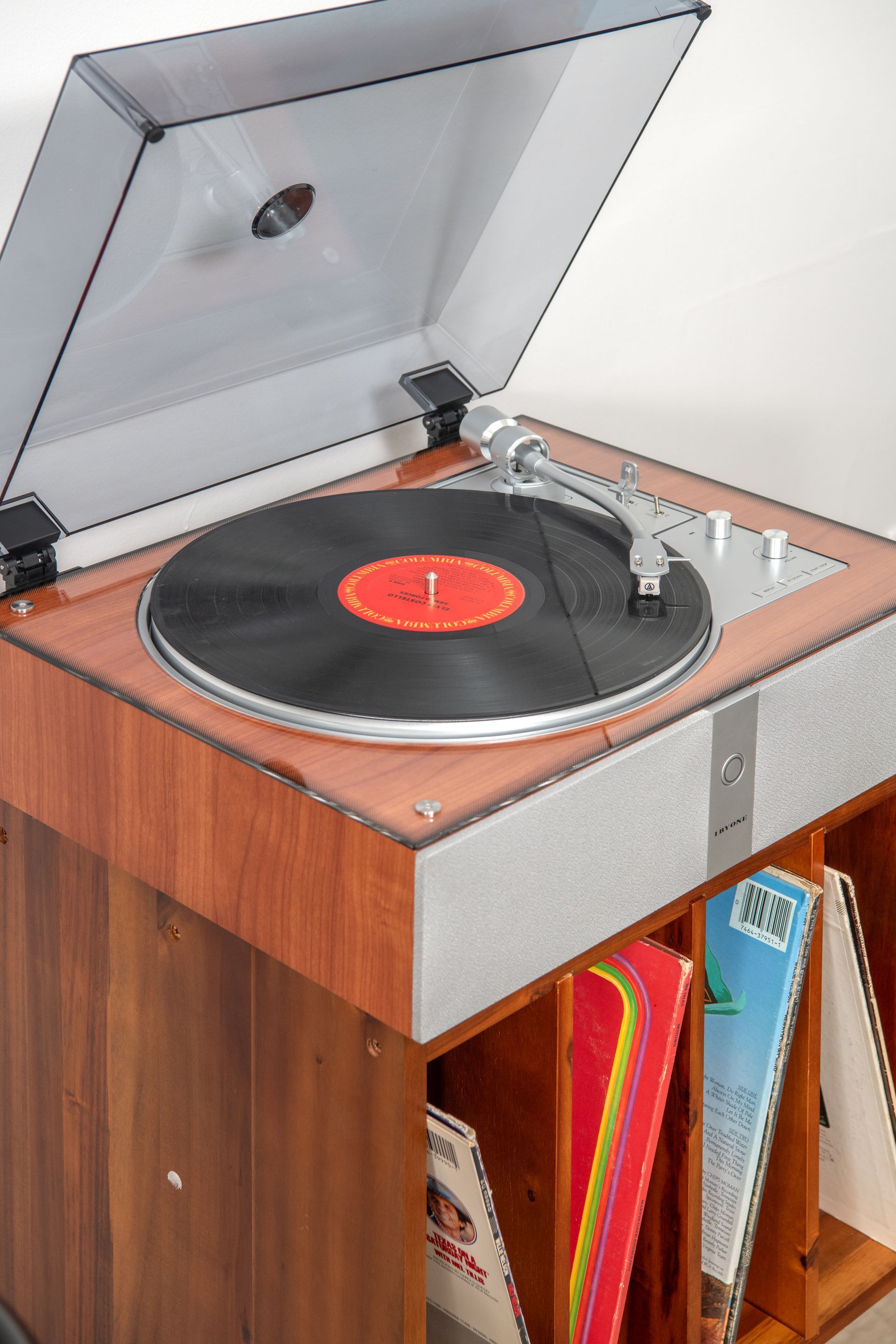 Vintage record player on a wooden cabinet with an open lid and a vinyl record playing.