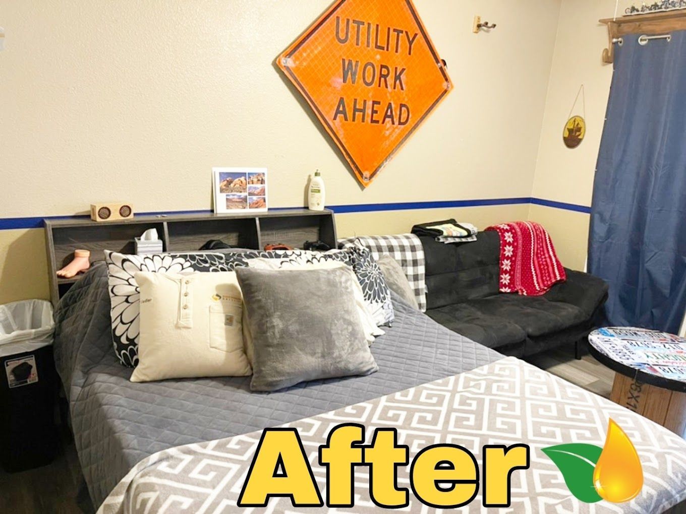 Bedroom with gray bedspread, pillows, wall art, and an orange “Utility Work Ahead” sign above the bed