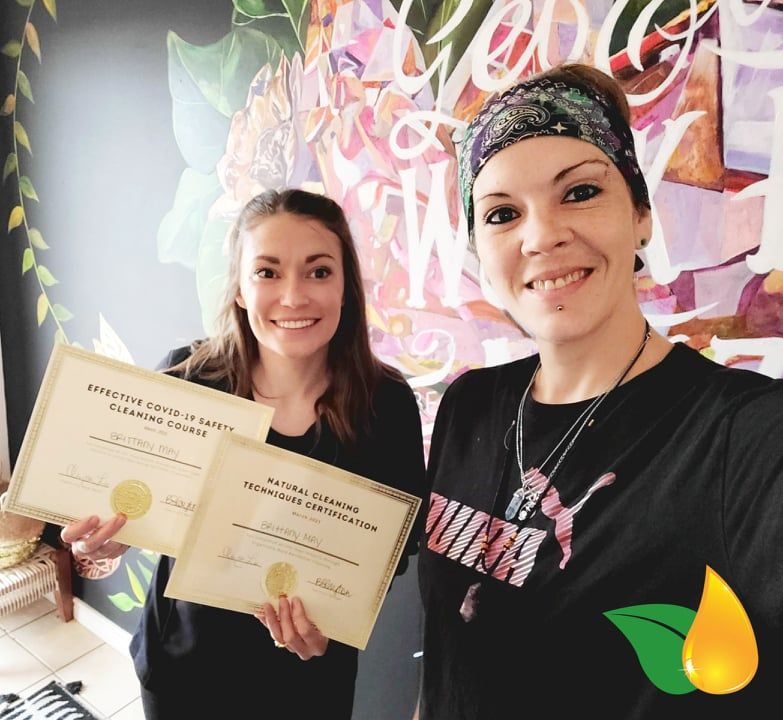 Two women holding certificates and smiling in front of a colorful mural