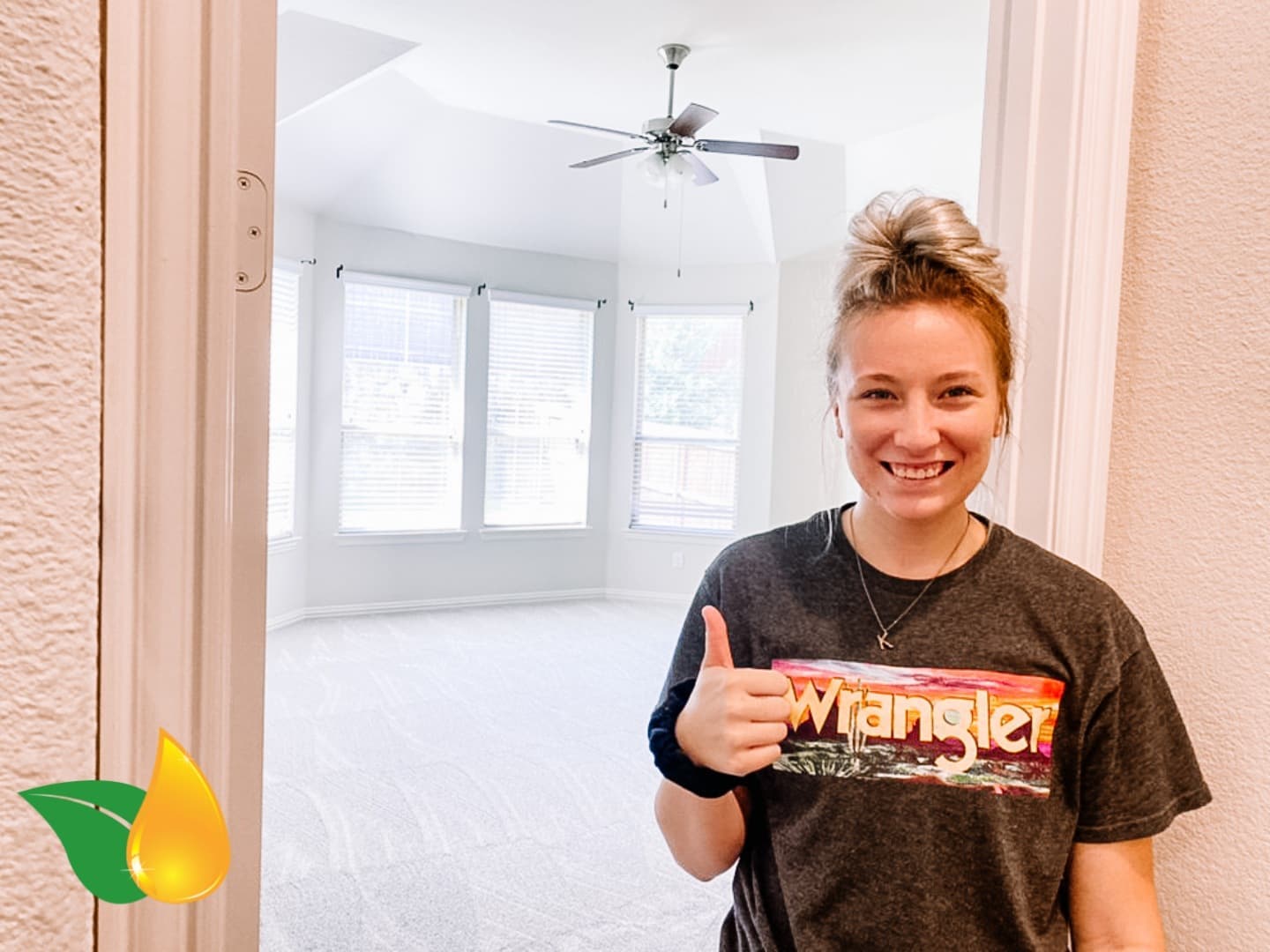 Woman smiling and giving a thumbs-up in an empty bright room
