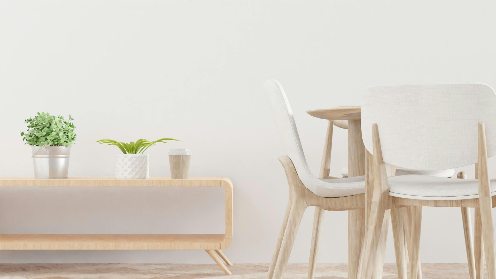 A minimalist room with a light wood sideboard holding potted plants and a small dining table with white chairs.