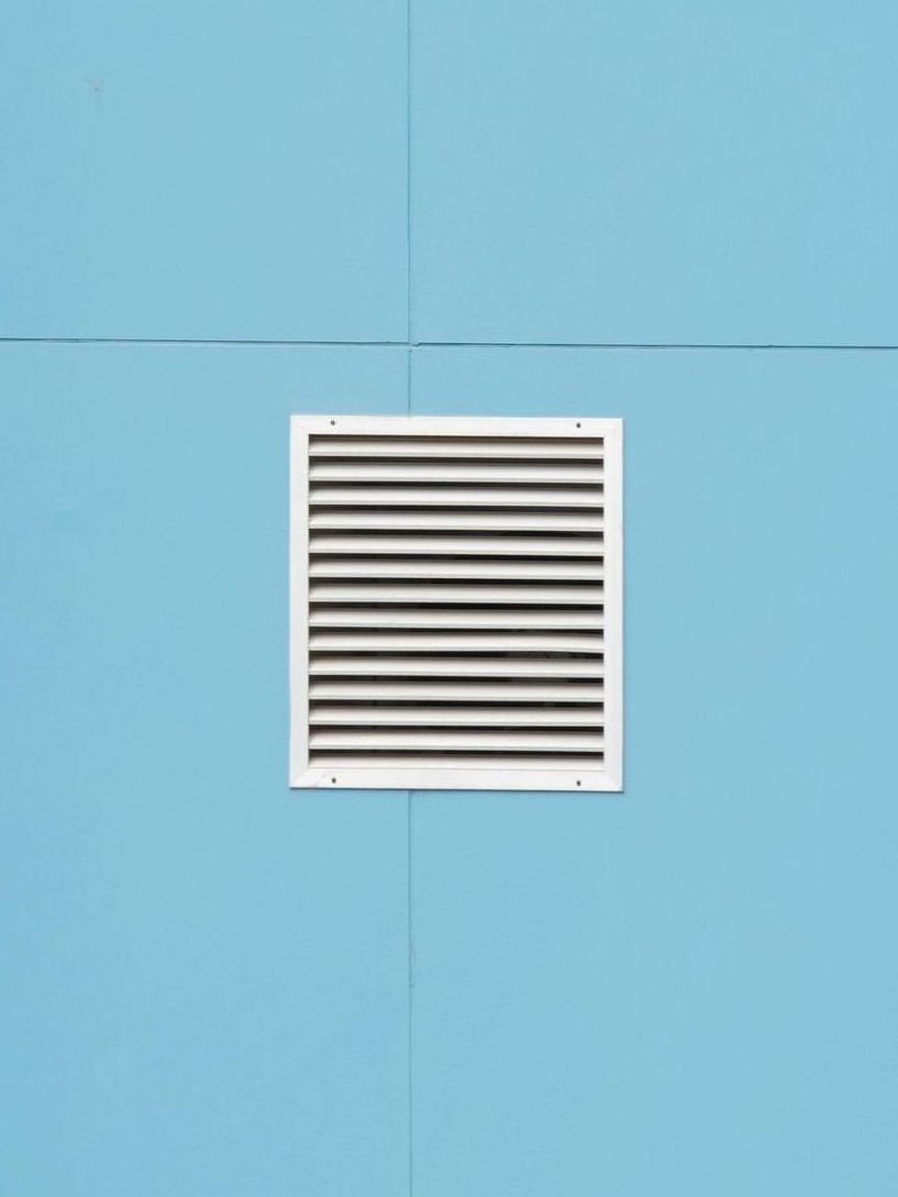 White vent grille on a blue wall panel.