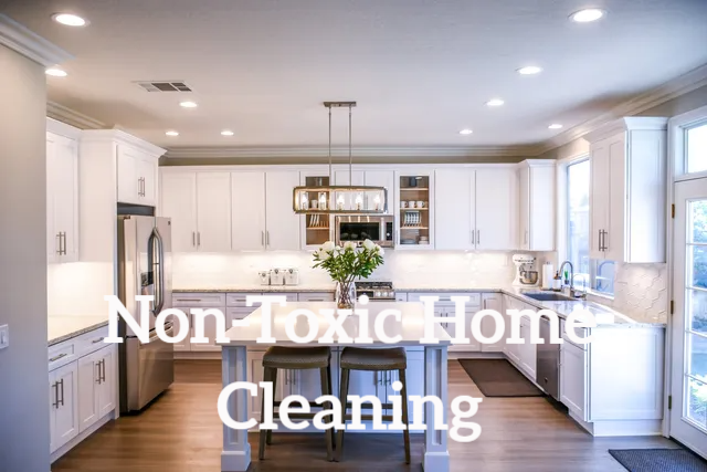 Bright white kitchen with island and the text “Non Toxic Home Cleaning” overlaid