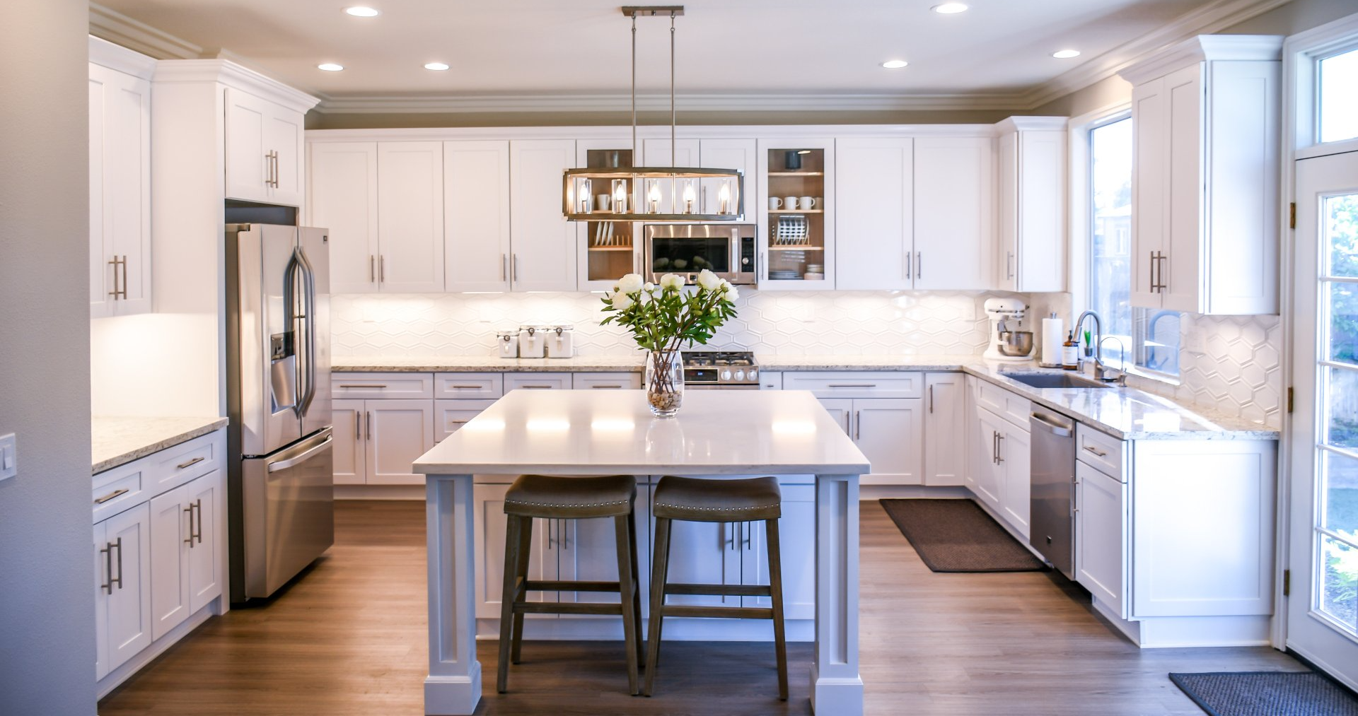 Bright modern kitchen with white cabinets, island, and stainless steel appliances