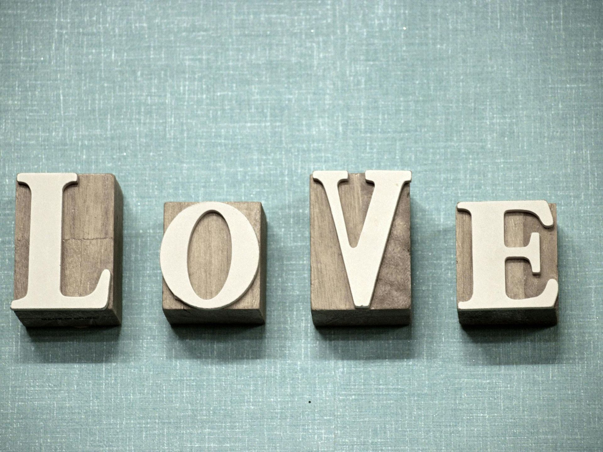 Wooden block letters spelling LOVE on a light blue textured background