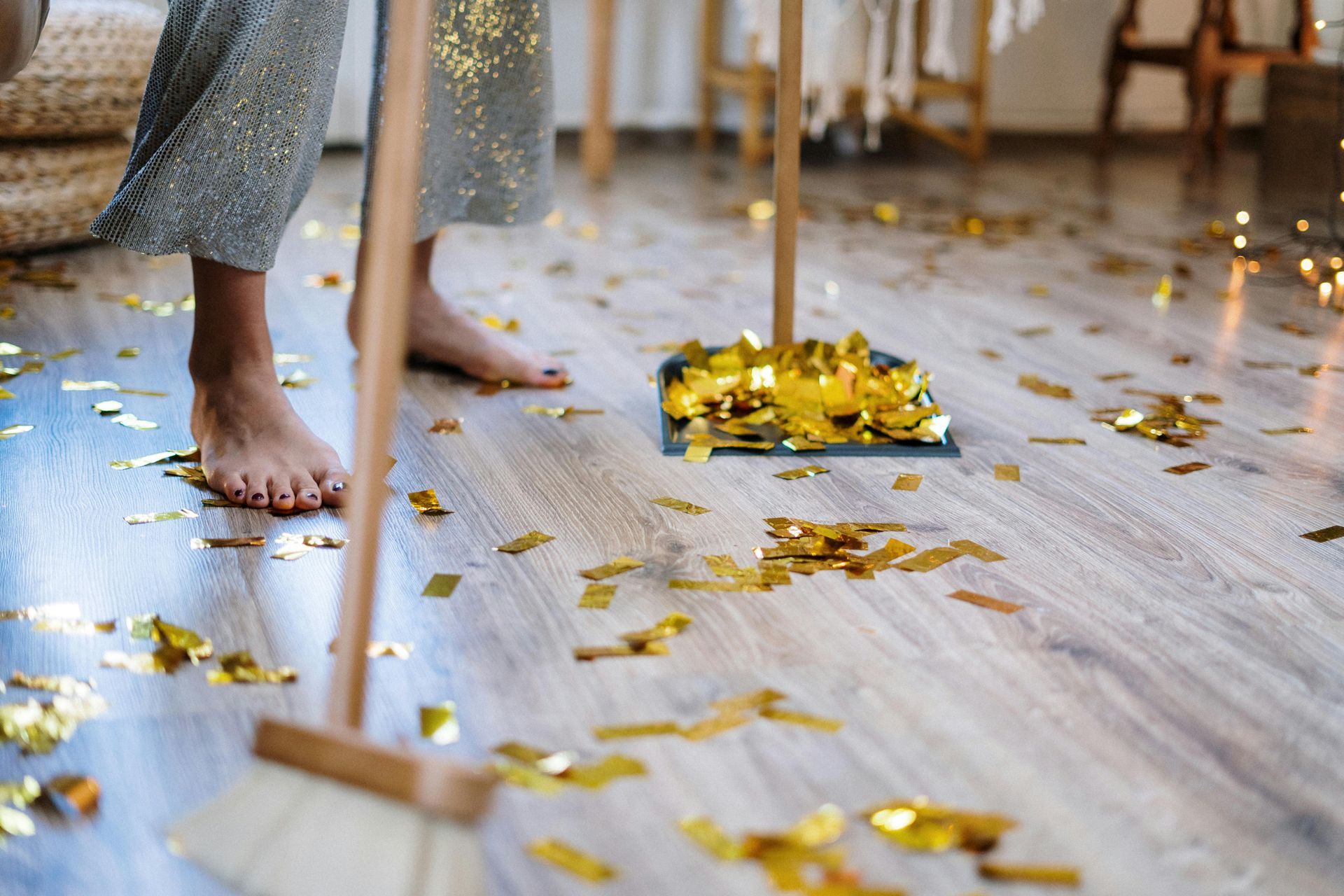 Bare feet near gold confetti on a wood floor, with a gift box in the background