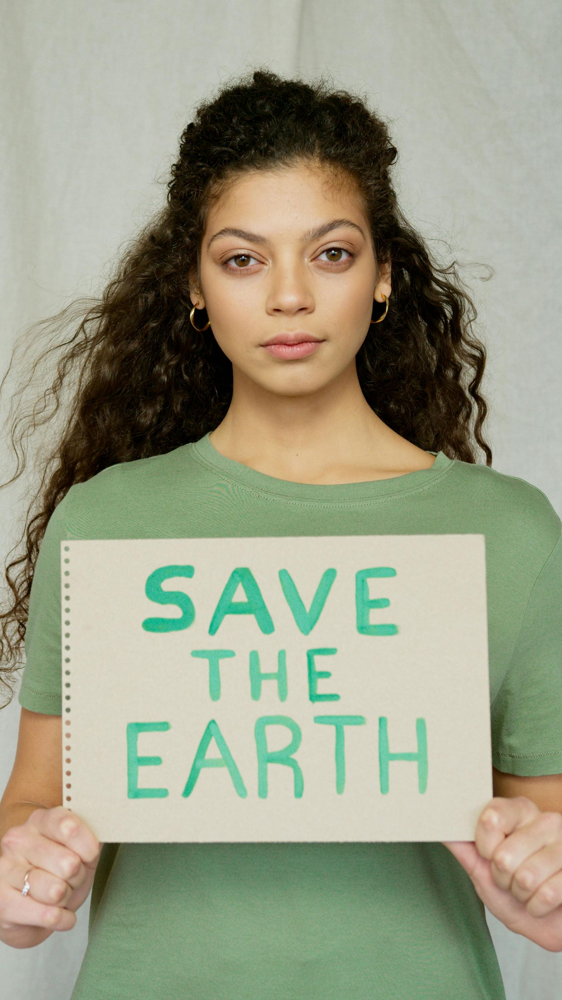 A person in a green shirt holds up a sign that says
