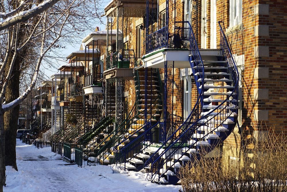 Une rangée de bâtiments en brique avec des escaliers bleus dans la neige.