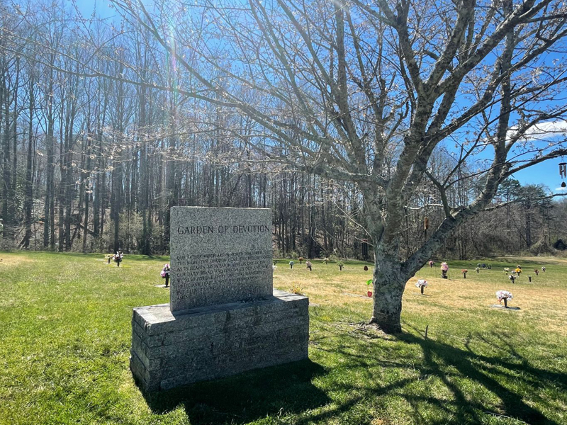 A gravestone in a cemetery with trees in the background.