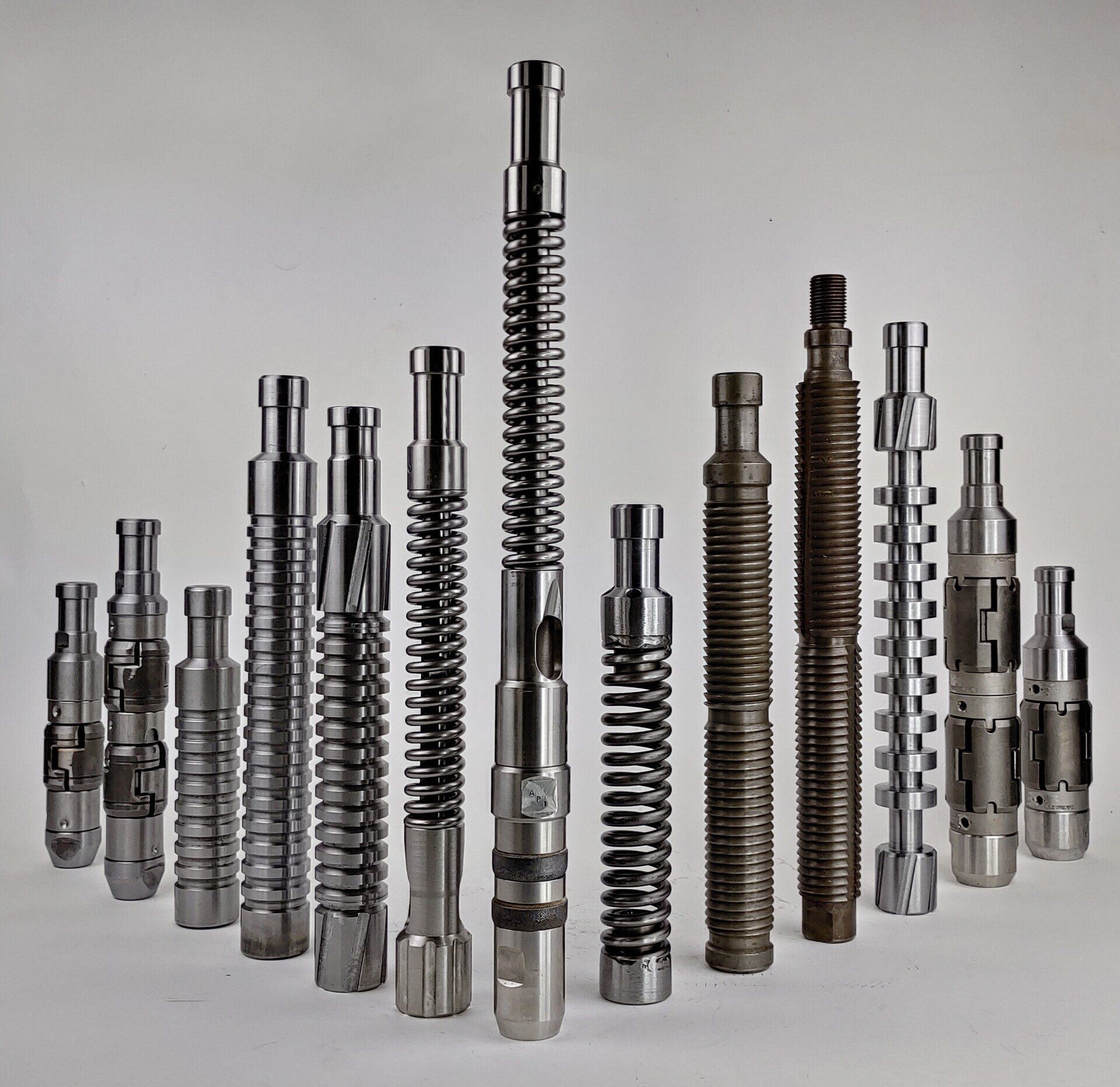 Assorted metal rods with varying designs, including spiral and grooved patterns, against a white background.