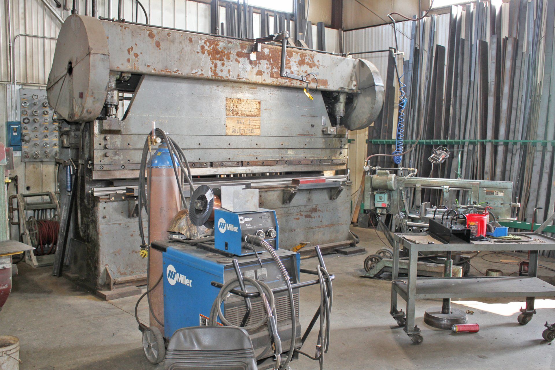 Industrial workshop with large press brake and welding equipment.