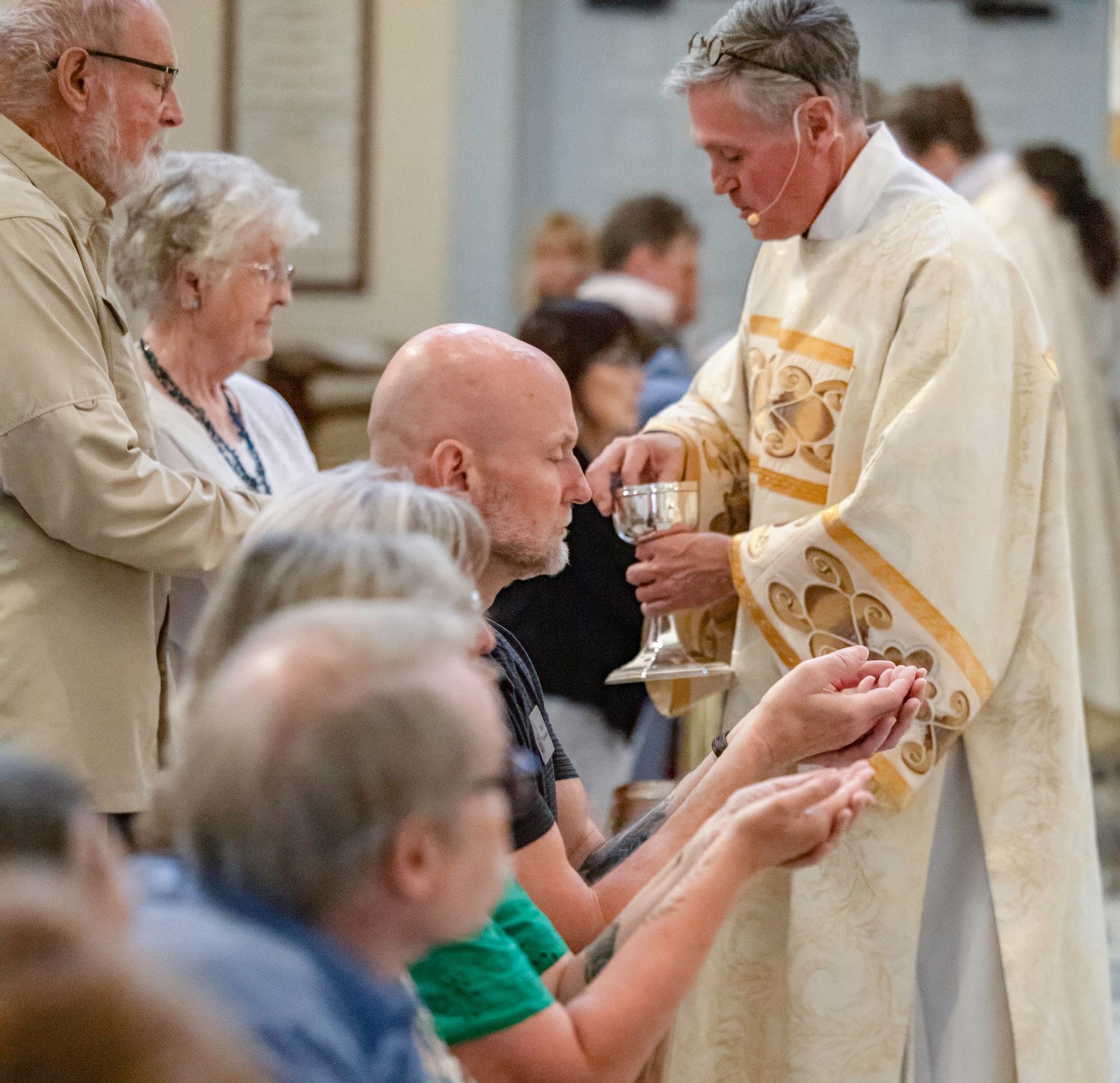Priest giving communion to seated worshippers in a church