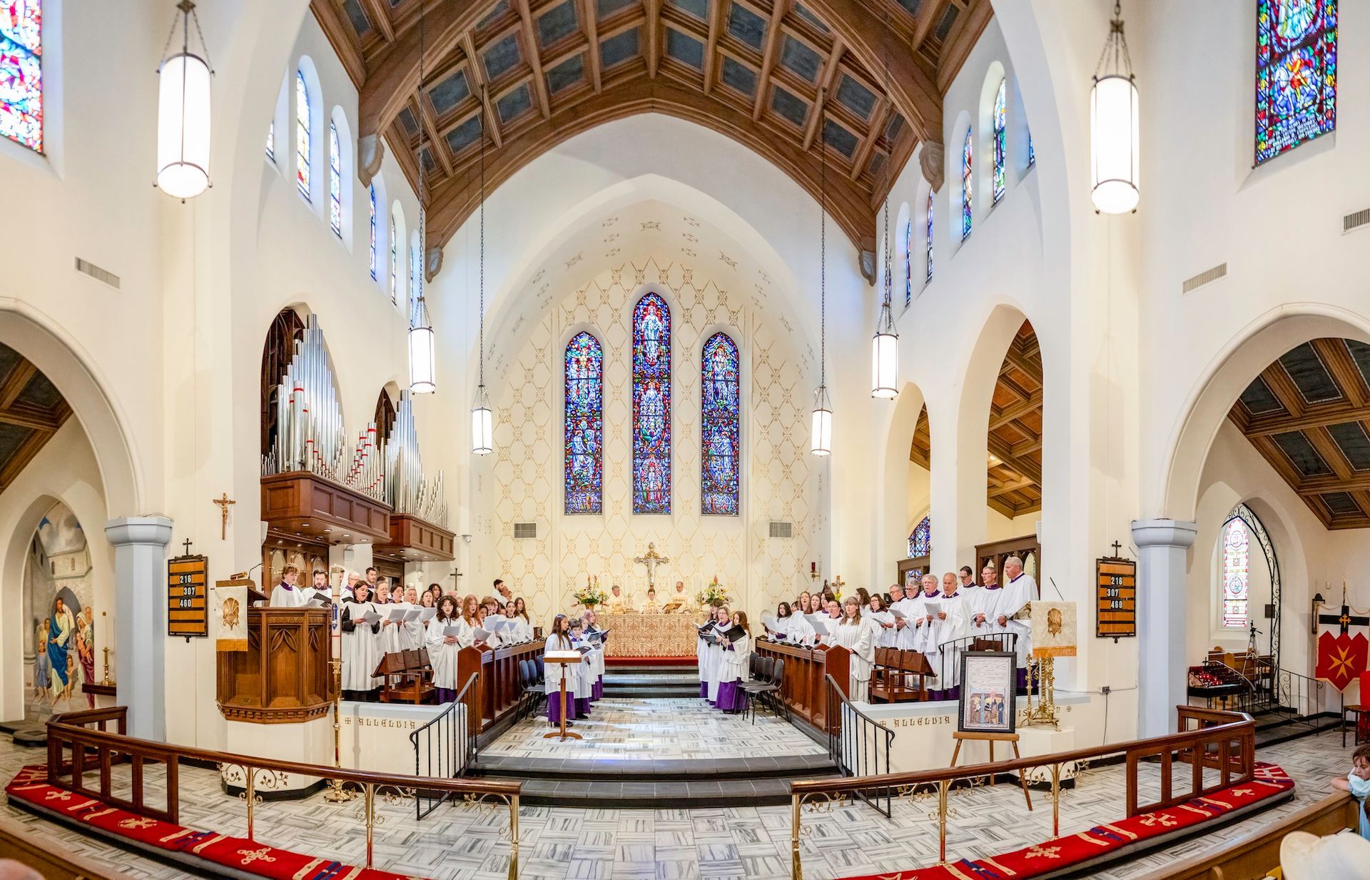 Bright Albuquerque Cathedral of St John's sanctuary with stained glass, wooden vaulted ceiling, altar, and people seated near the front