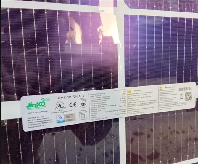 Close-up of Jinko solar panel with product label and warning stickers