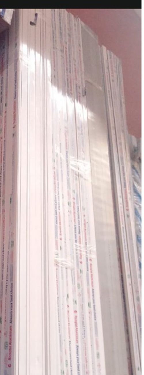 Tall stack of white papers or folders with small printed text, viewed close up against a pink wall