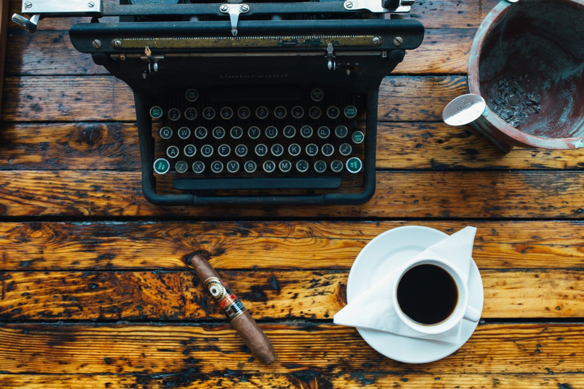 Typewriter on rustic wooden table with coffee cup and pen