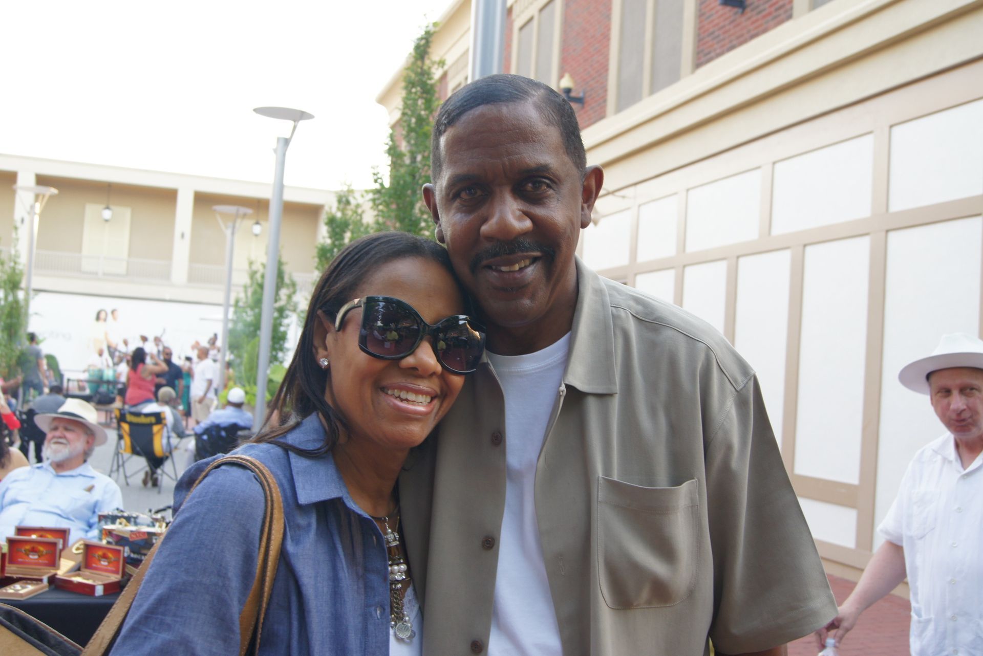 Two people smiling and posing together outdoors in a courtyard.