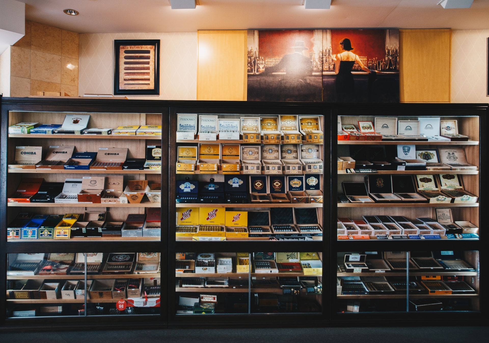 Display of packaged products on black shelves in a store, with framed wall art above.