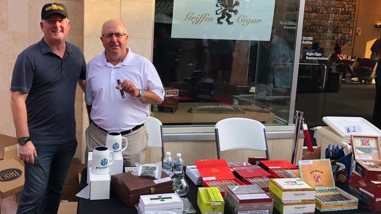 Two men standing behind a table of books and items outside a storefront
