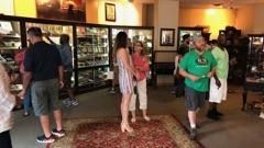 People browsing books in a warmly lit bookstore, standing and walking among shelves.