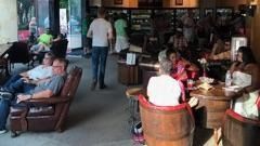 People sitting at a cafe, with a server walking through the indoor seating area.