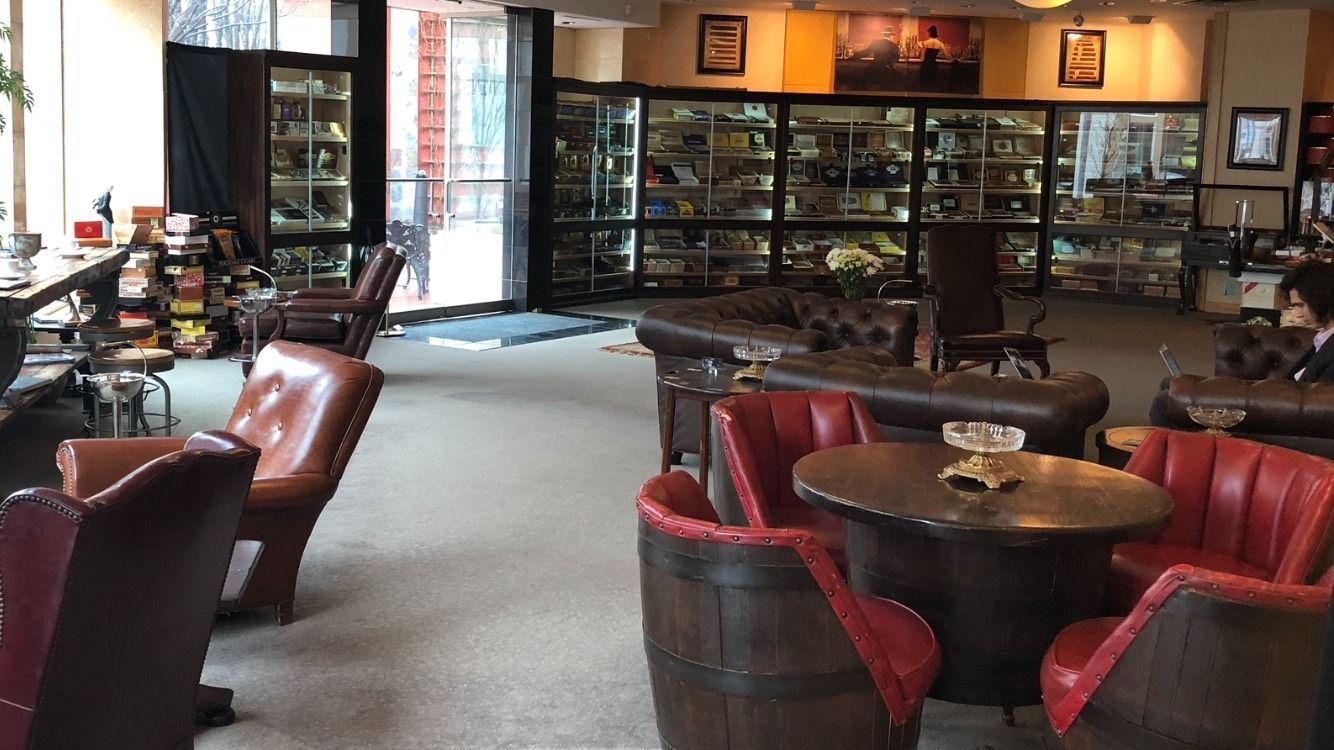 Cozy café lounge with red leather chairs, wooden tables, and display cases along the back wall