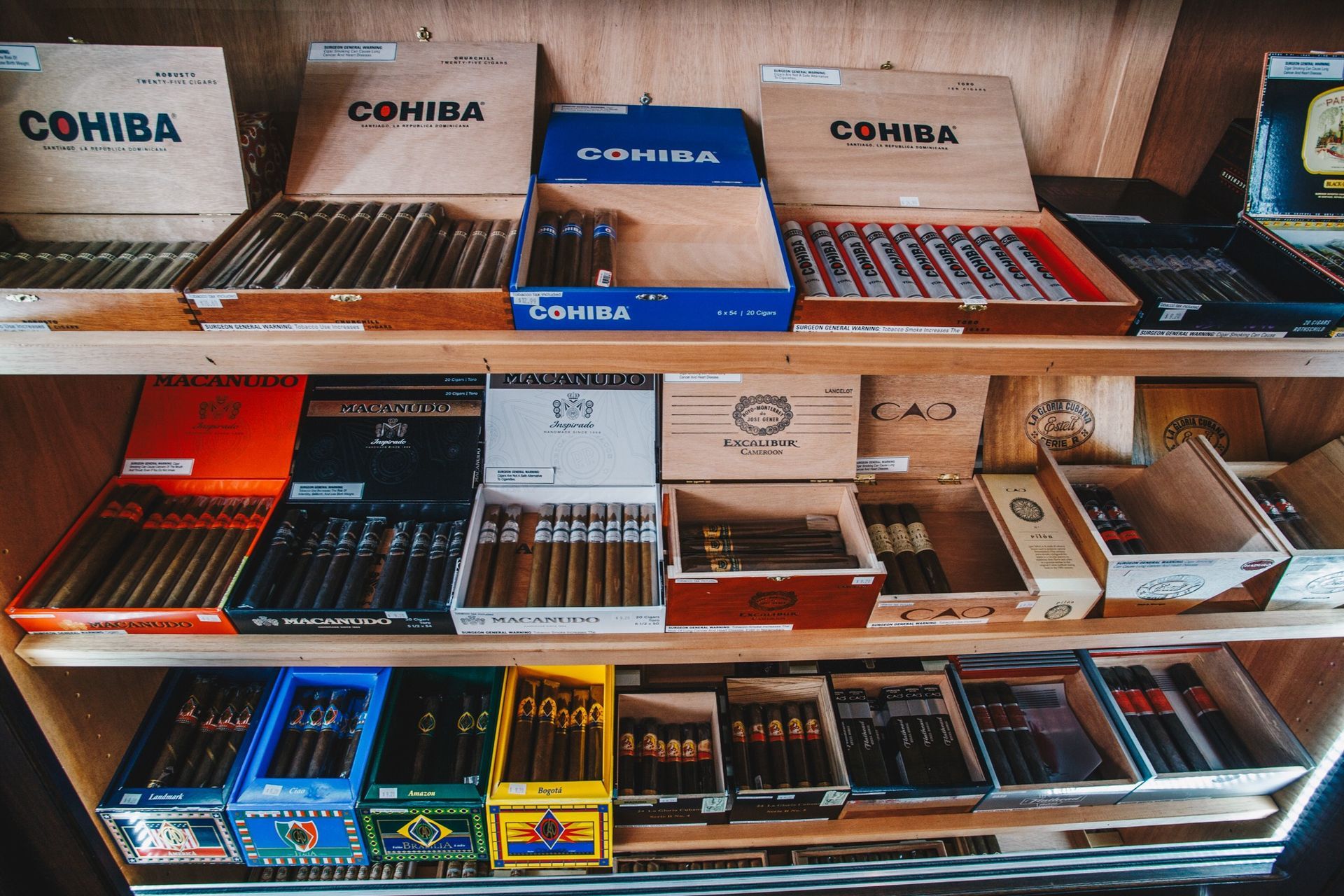 Assorted cigar boxes and packs displayed on store shelves in a tobacco shop