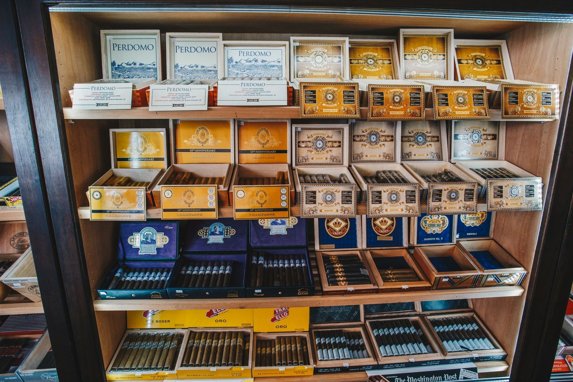 Shelves of assorted cigar boxes and packs in a wooden display case.