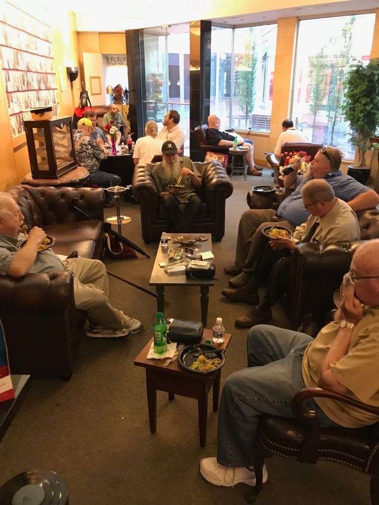 People seated in a cozy living room, chatting in a circle around a coffee table.